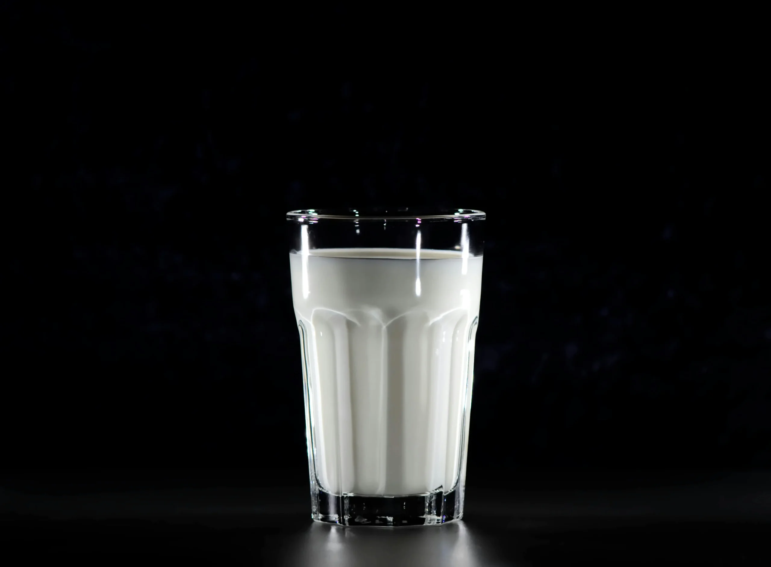 A glass of fresh milk served with a stack of cookies on a rustic wooden table, perfect for a comforting snack